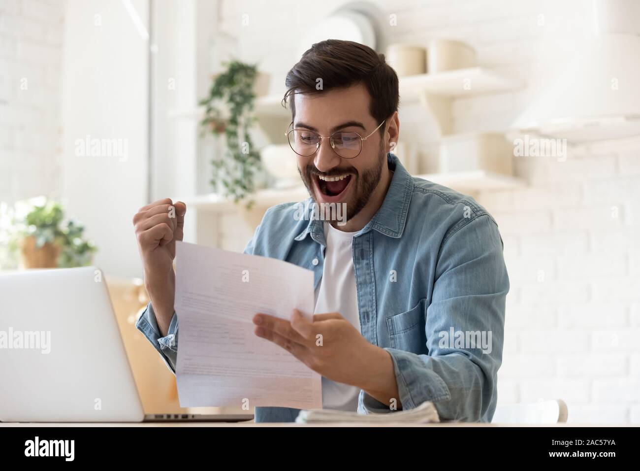 Uomo eccitato la lettura di posta lettera contentissimo dalla buona novella Foto Stock