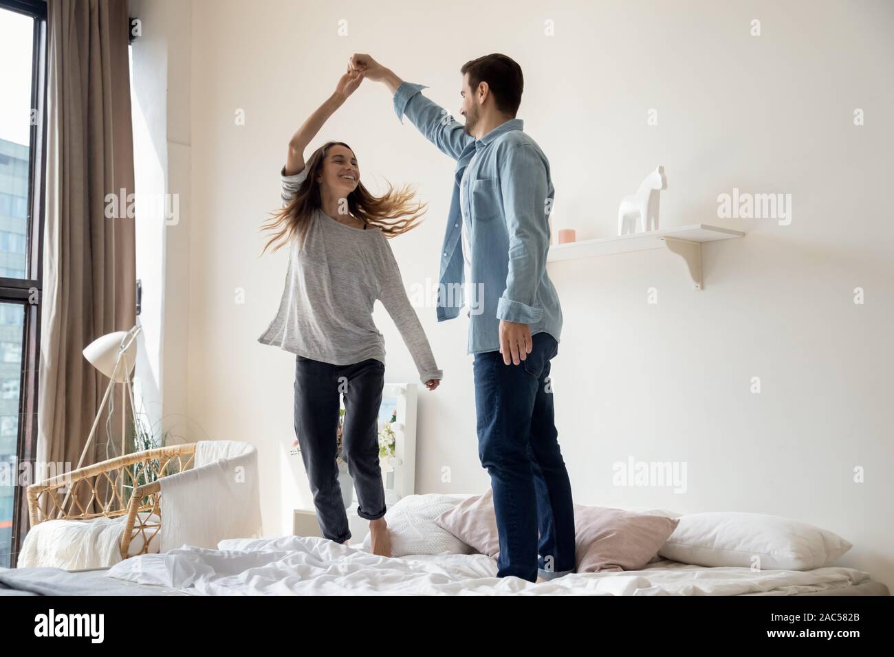 Romantica spensierata coppia giovane divertirsi ballando sul letto Foto Stock