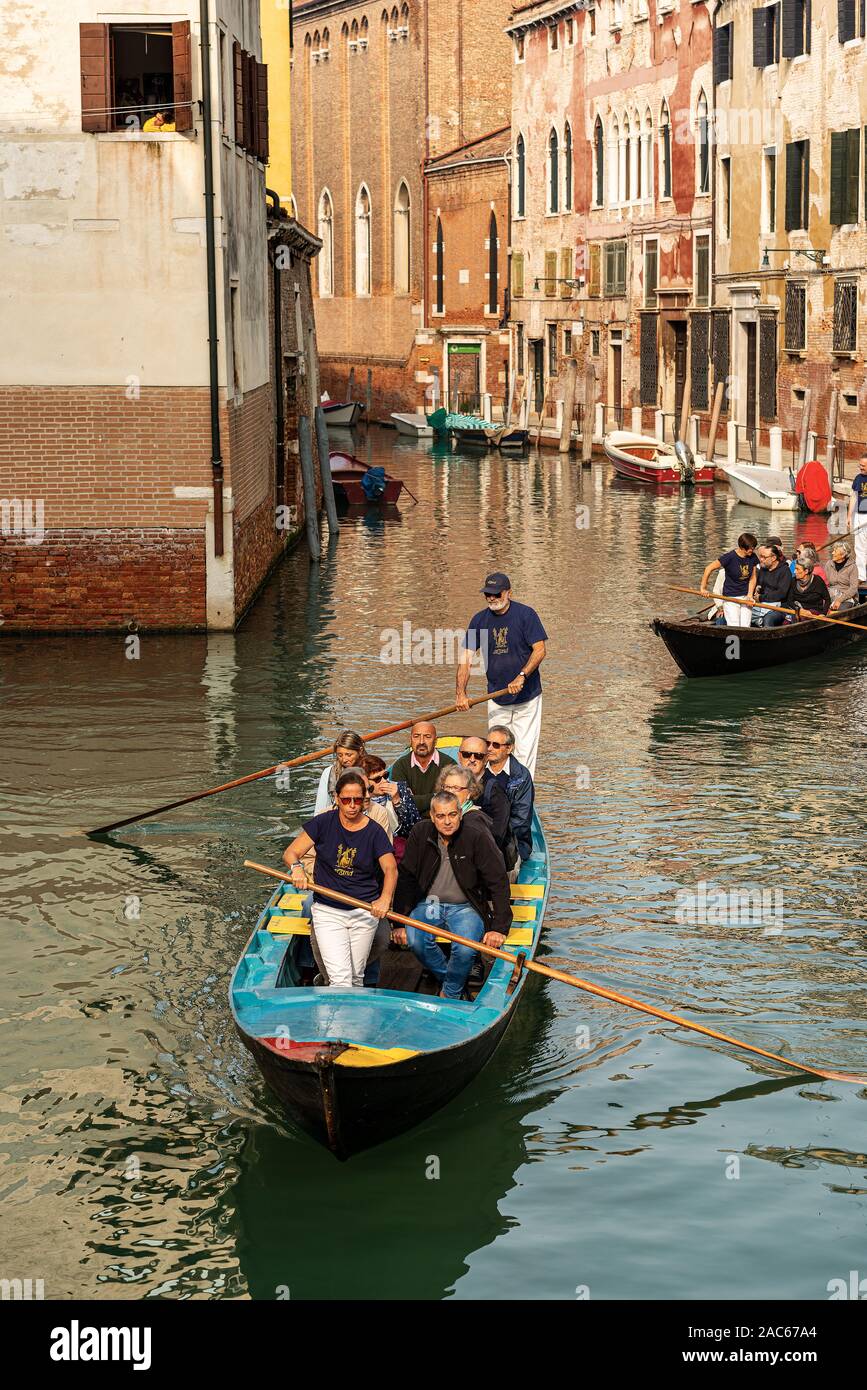 Venezia, un gruppo di turisti a bordo di due antiche in legno barche a remi fare un tour attraverso i canali della laguna veneta. L'Italia, Europa Foto Stock