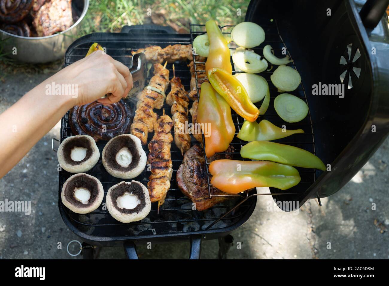 Prepareing barbeque in mezzo alla natura con funghi, pepperс, bistecchine , shishs Foto Stock