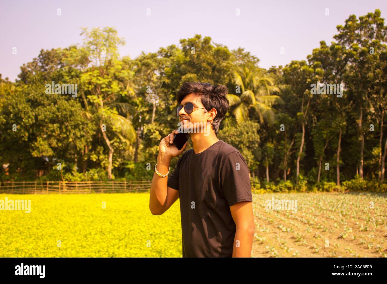 Un giovane ragazzo in posa con il suo telefono cellulare, ricerca rete mobile nel paese, lo sfondo è la natura. Foto Stock