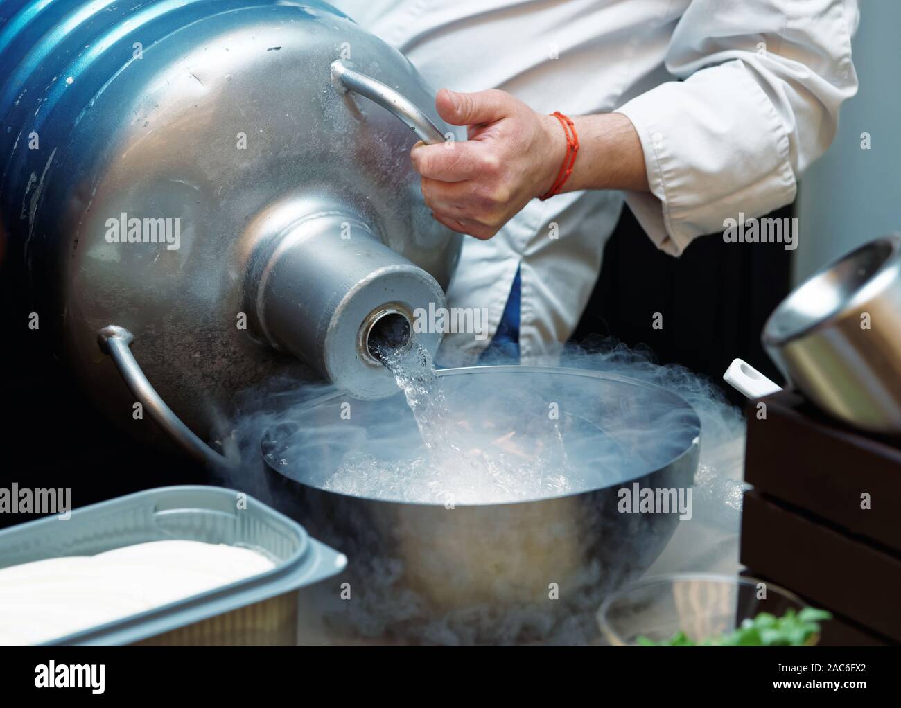 Lo chef è colata di azoto liquido da un grande recipiente Dewar, tonica immagine Foto Stock