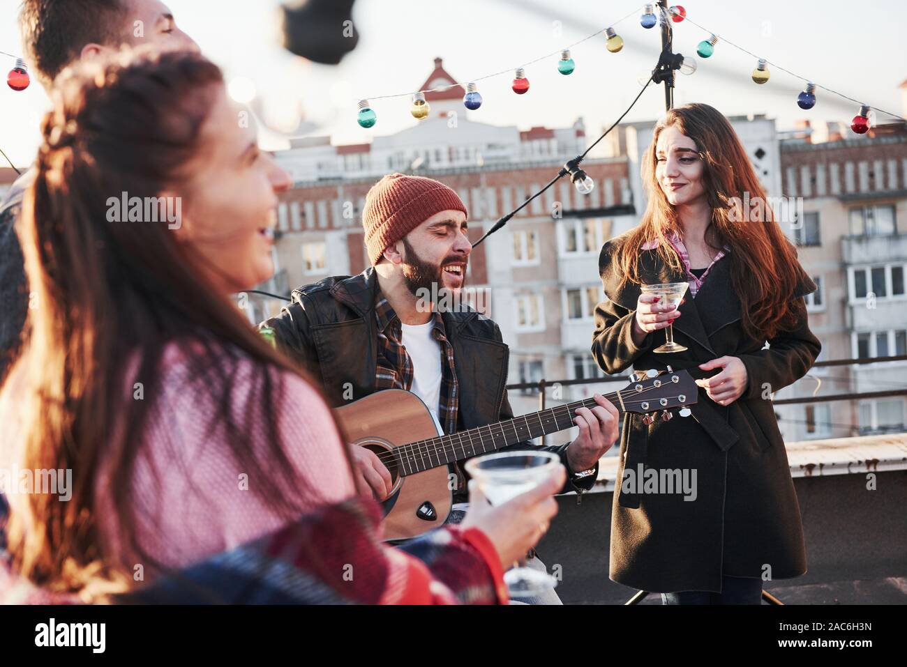 Sento come l'anima del canto. Giovani amici sono partito con alcool e chitarra presso la terrazza sul tetto Foto Stock