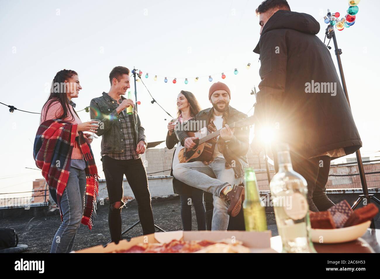 Splendido sole. Tabella con il cibo. Weekend sul tetto con chitarra, alcol e pizza Foto Stock