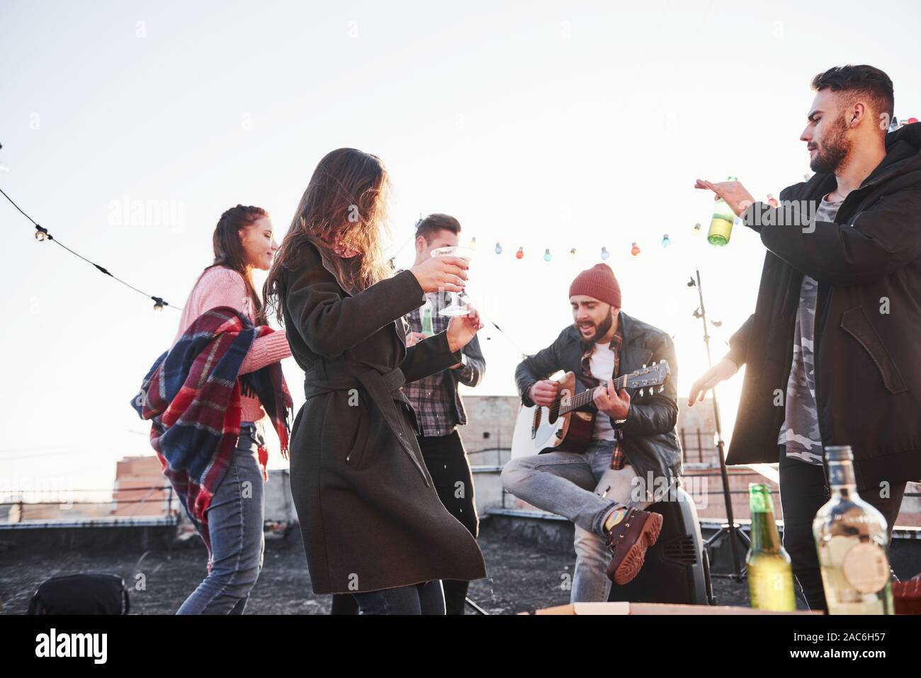 In tutti la canzone preferita. Tetto a qualche festa con consumo di alcool e di suonare la chitarra. Sunshine dietro Foto Stock