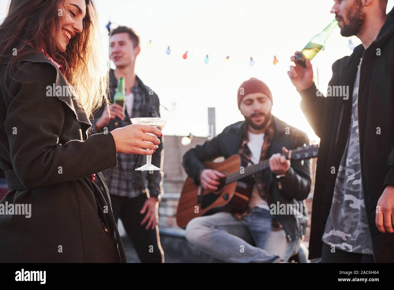 Focus sulla bella ragazza felice. Tetto a qualche festa con consumo di alcool e di suonare la chitarra. Sunshine dietro Foto Stock