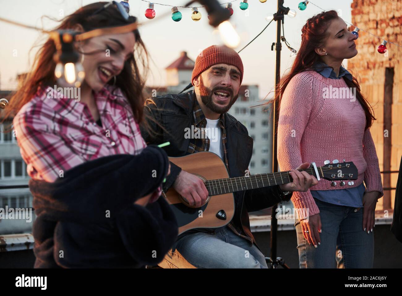 Toccare l'anima. Tre amici godere cantando la chitarra acustica brani sul tetto Foto Stock