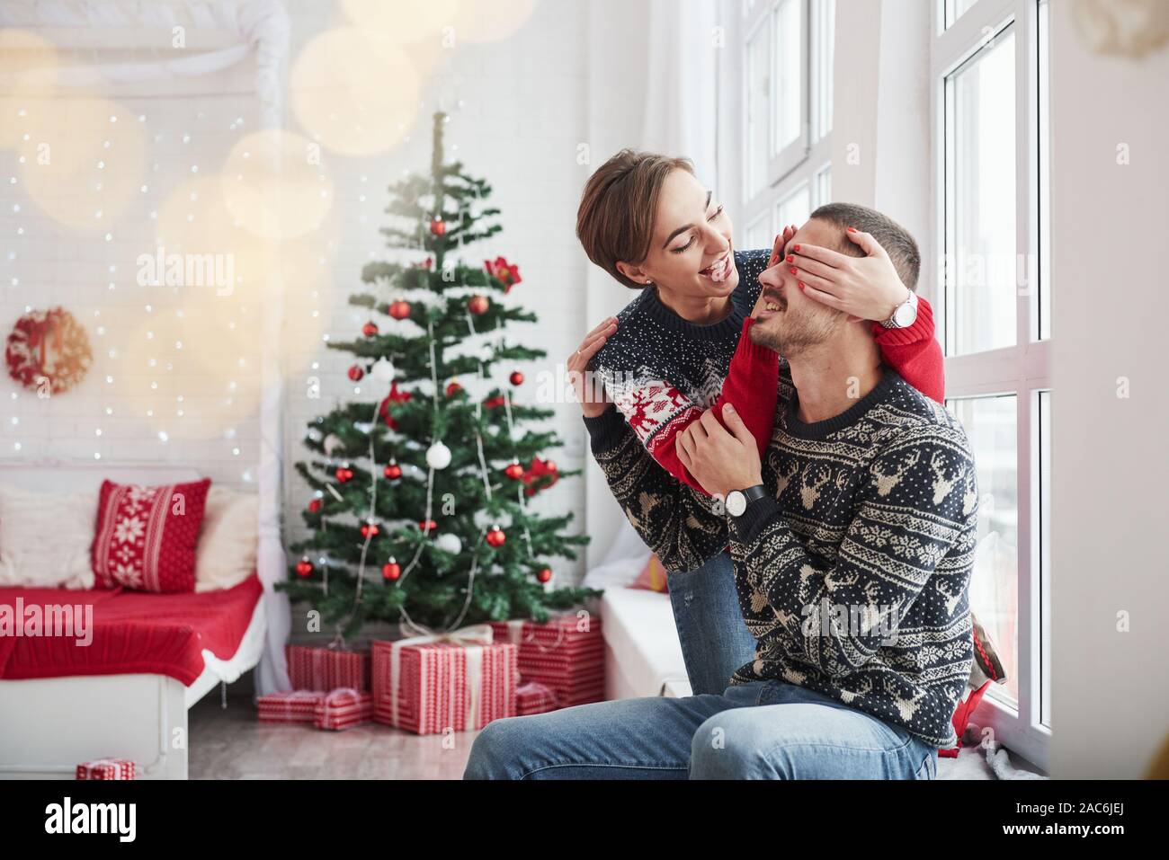 Indovina cosa dono che io darò a te. Felici i giovani si siede sul davanzale in camera con decorazioni di Natale Foto Stock