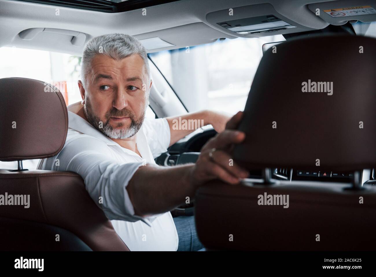 La prova del veicolo. Alla guida di una vettura in retromarcia. Guardando dietro. L uomo nella sua nuovissima automobile Foto Stock