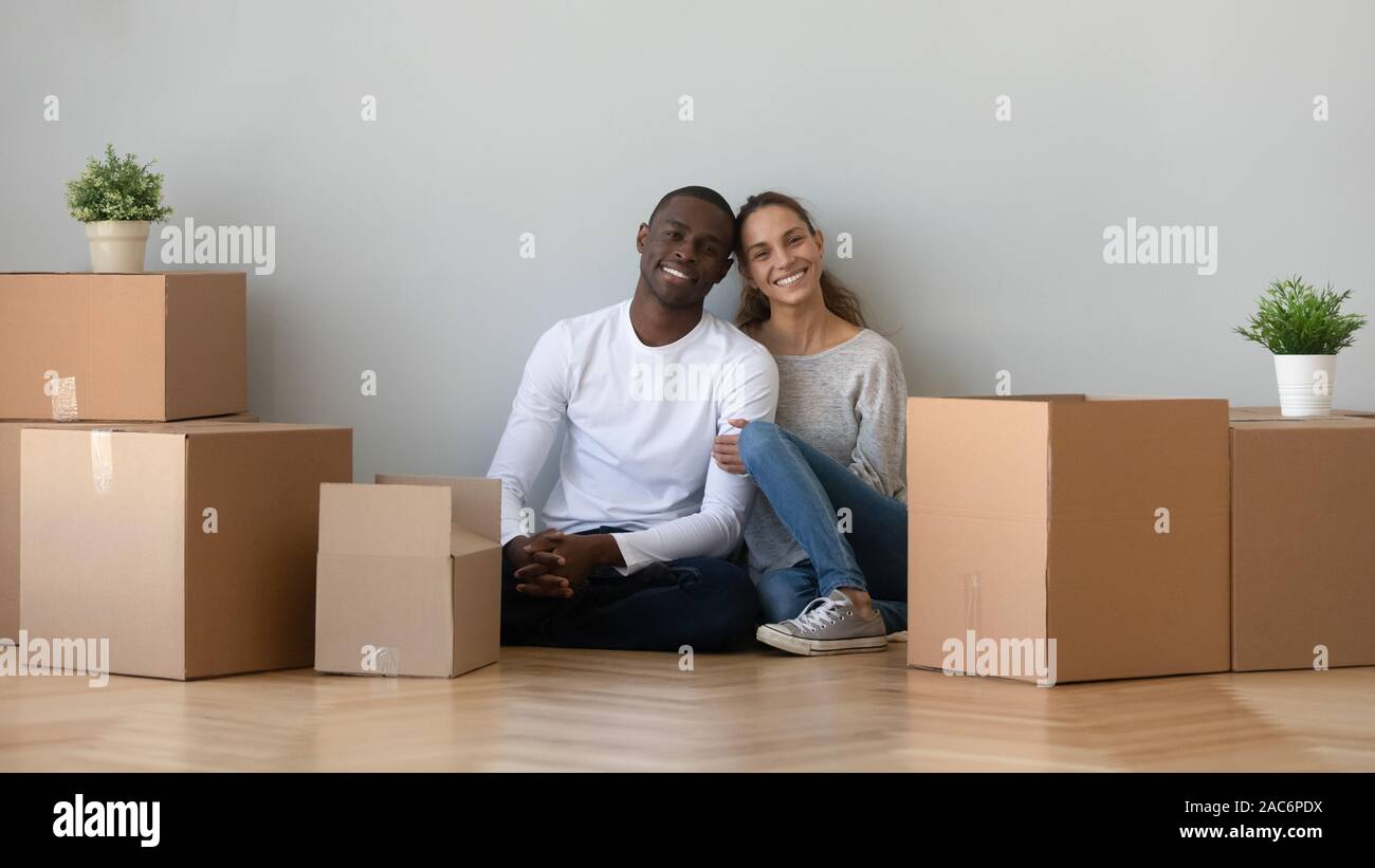 Sorridenti giovani razza mista famiglia giovane seduto sul pavimento. Foto Stock