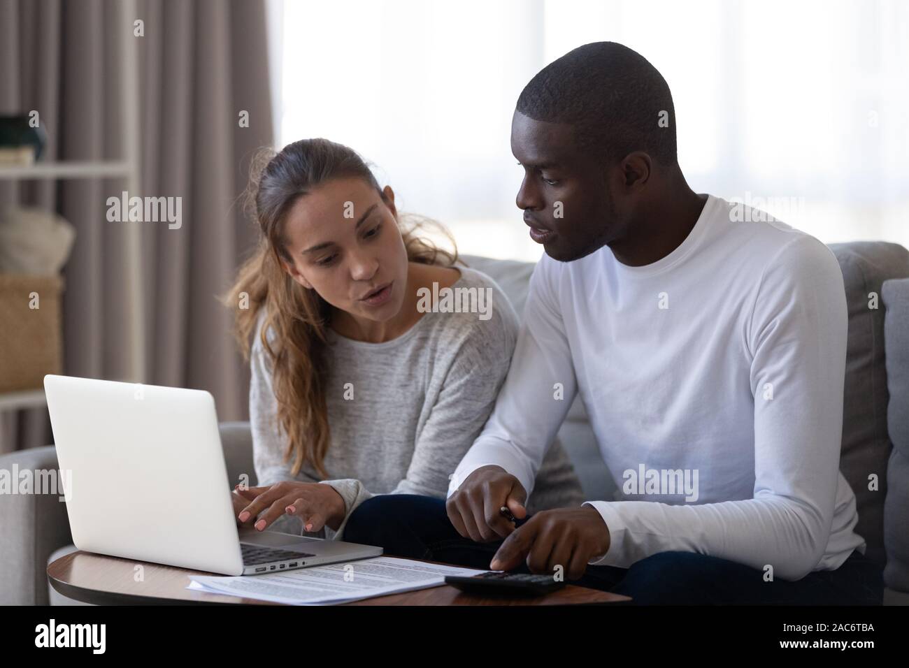La millenaria multirazziale coppia sposata il calcolo mensile bilancio familiare. Foto Stock
