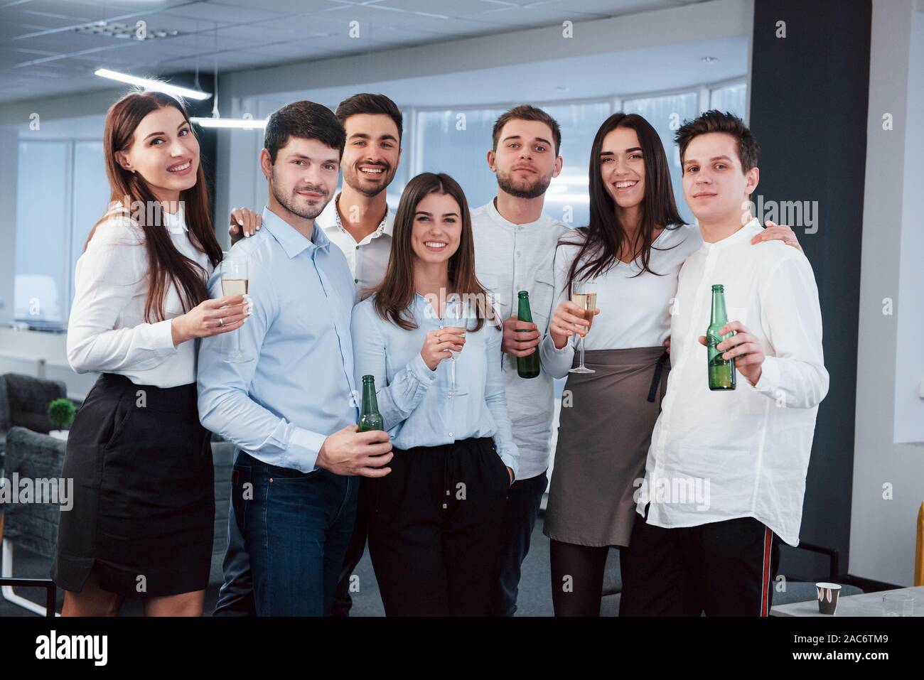 Avente un buon tempo. Foto del giovane team in abbigliamento classico tenendo un drink nel moderno buona ufficio illuminato Foto Stock