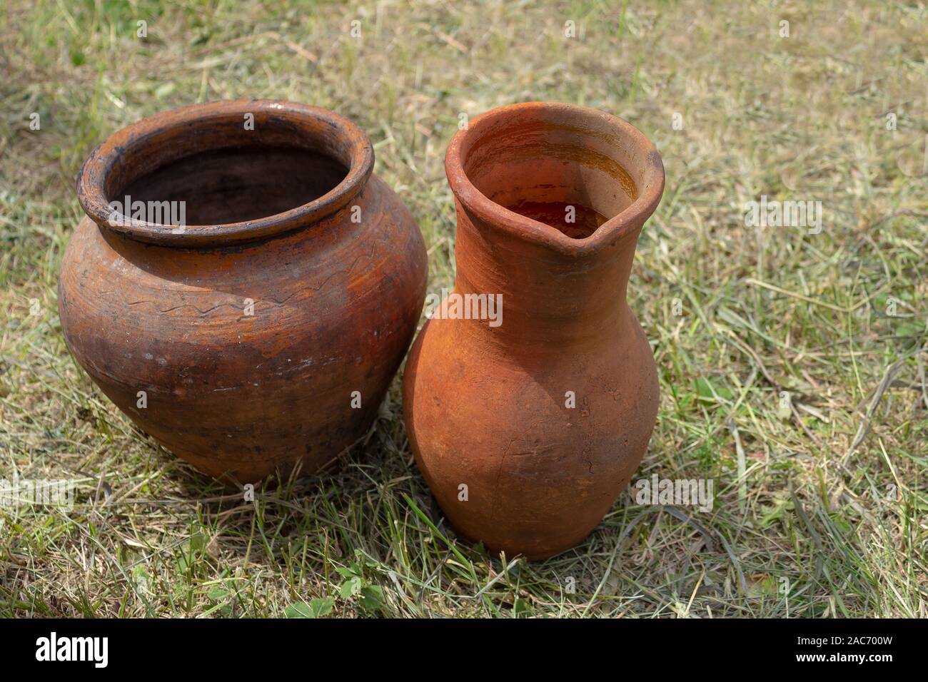 Un antico pentola di creta e un vaso sono impostati su erba sotto sale aperte. Vero e proprio degli articoli per la casa del passato. Foto Stock