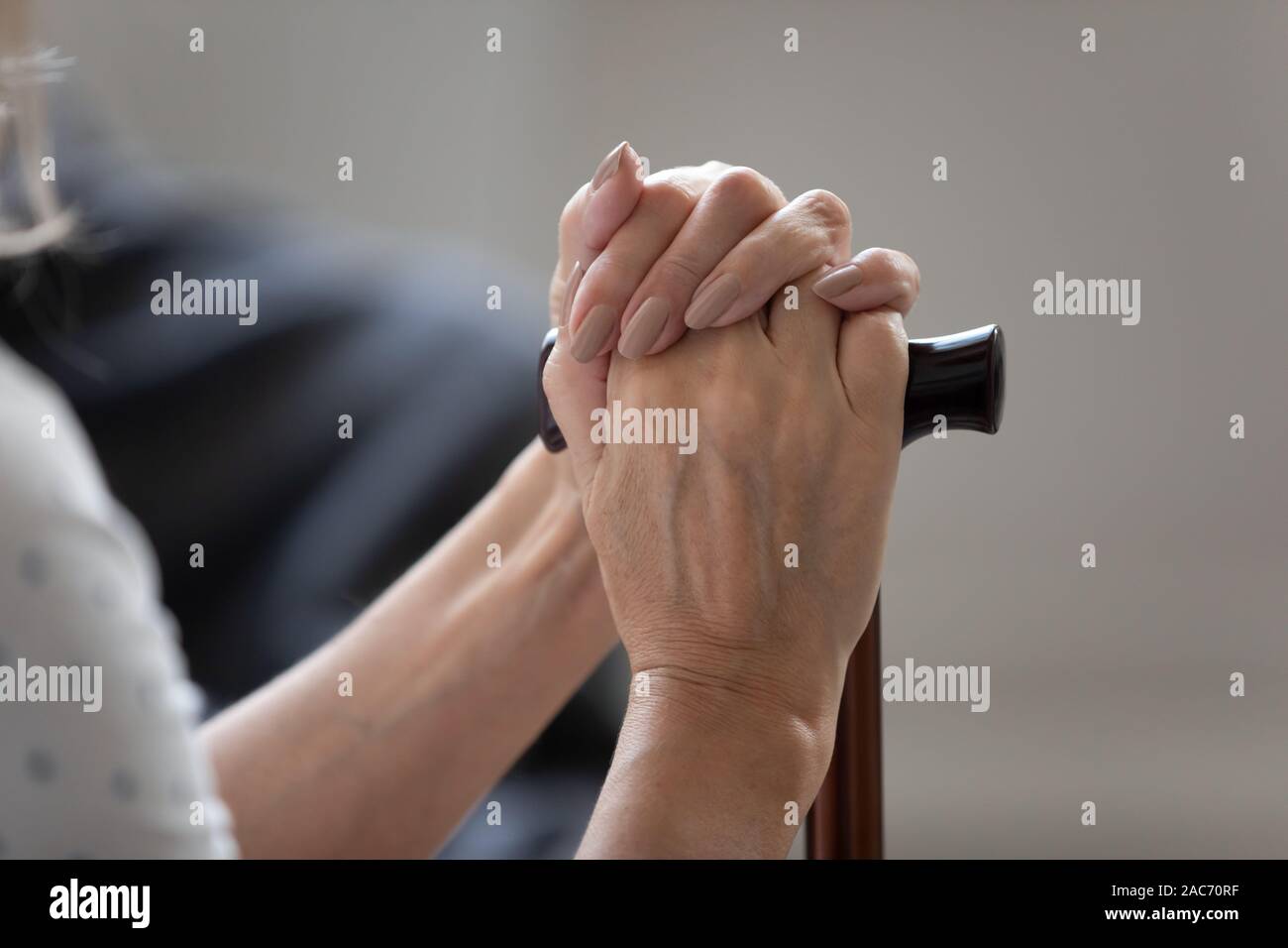 Primo piano immagine femmina vecchie mani bastone seduto al chiuso Foto Stock