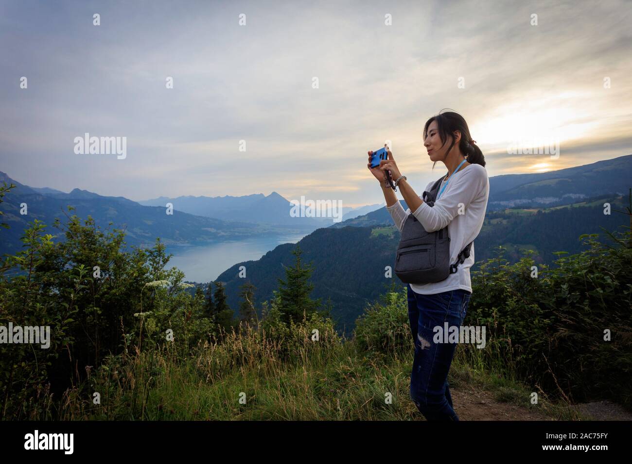 Una donna scatta una foto del lago Thun da Harder Kulm, Interlaken, Svizzera Foto Stock