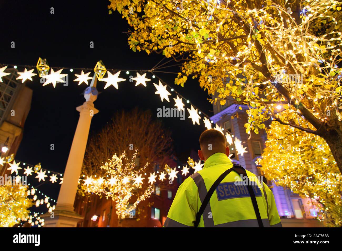 La guardia di sicurezza con giacca gialla sul dovere di Natale in Covent Garden, Londra Foto Stock