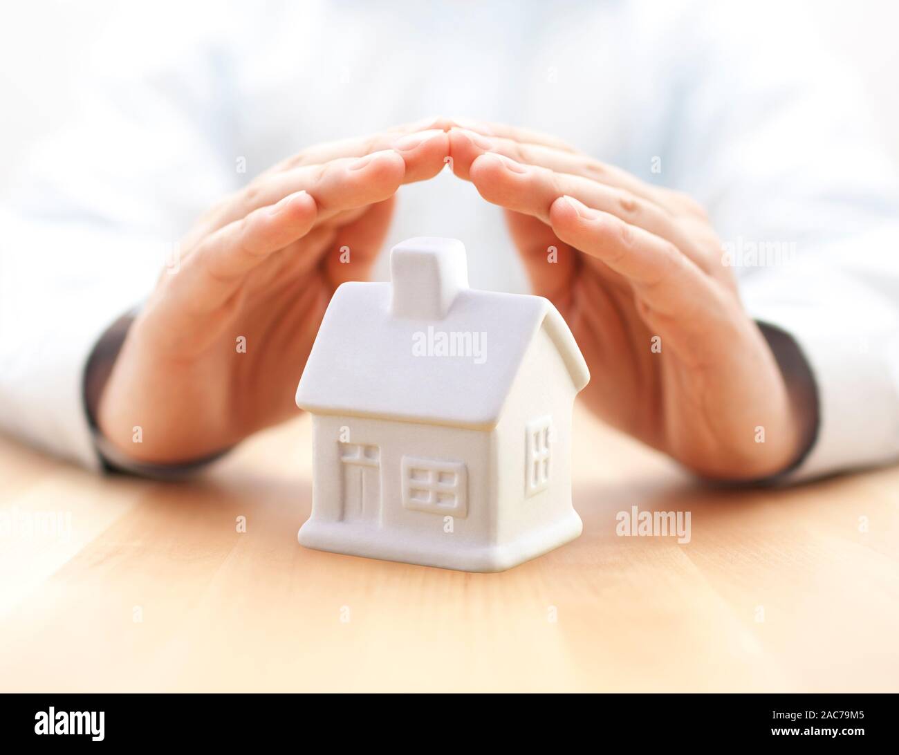 Proteggere la vostra casa. Piccola casa bianca toy coperti da mani Foto Stock