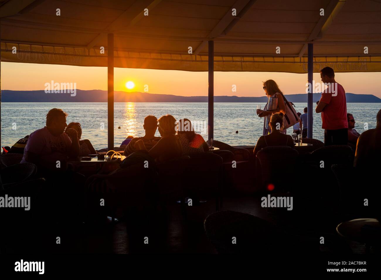 Gli ospiti in un ristorante sul mare sull'isola di Cres guardare il tramonto sulla baia di Kvarner, Croazia Foto Stock