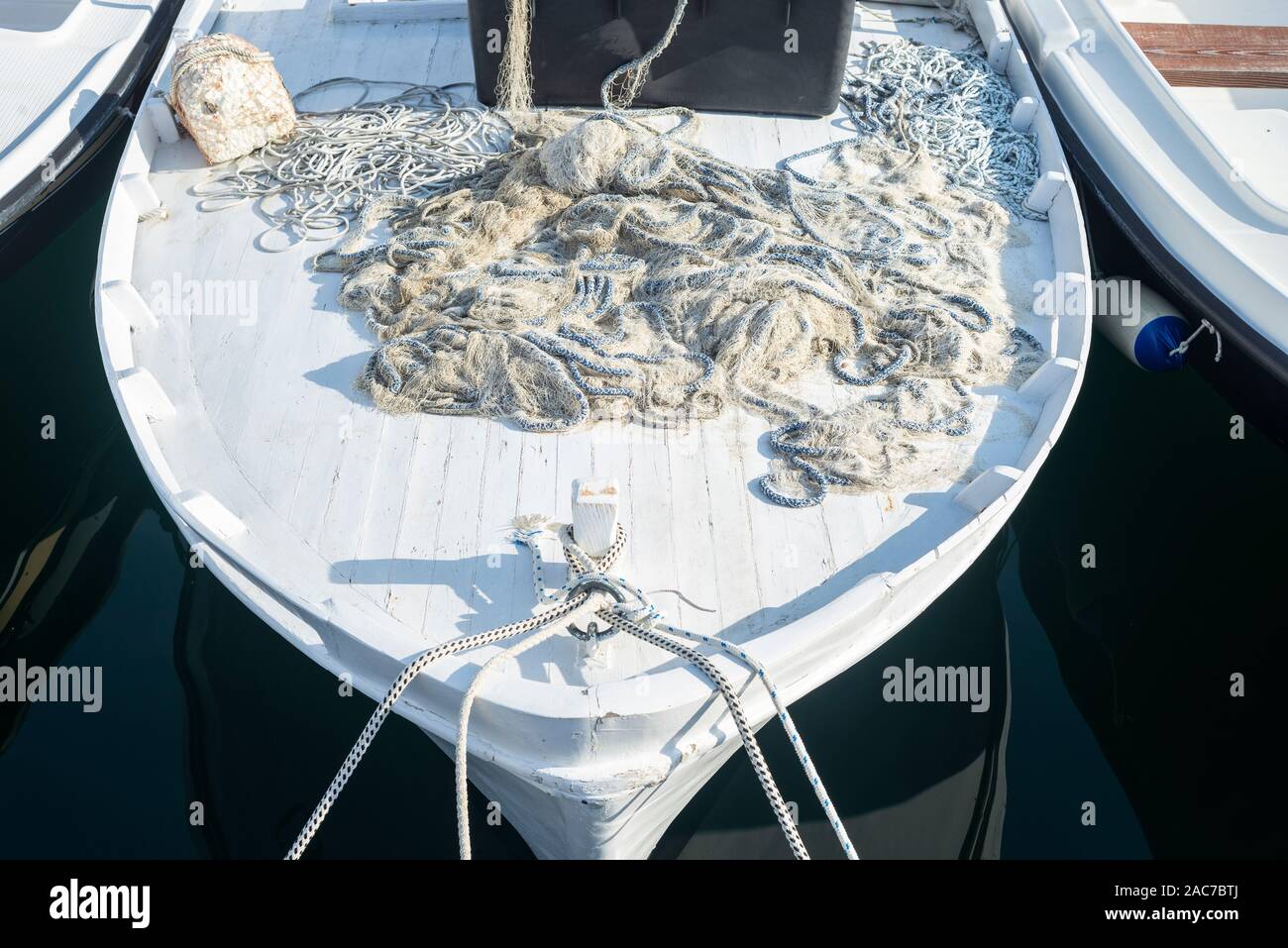 White barca da pesca con corda e rete da pesca sul ponte si illumina intensamente al sole del mattino nel porto di Cherso, baia di Kvarner, Croazia Foto Stock