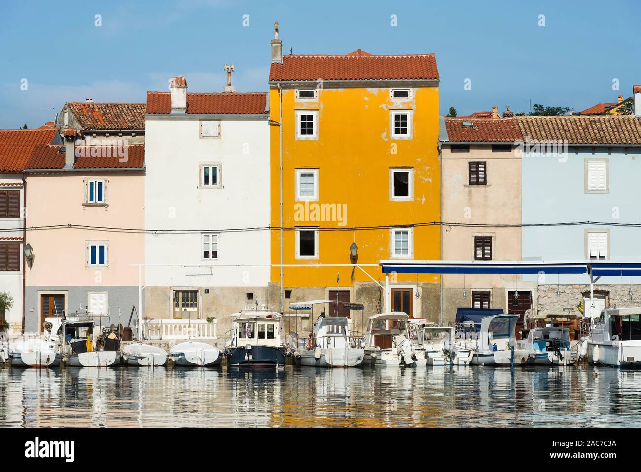 Facciate colorate nel porto della città vecchia di Cres brillano al sole di mattina e sono riflessi nell'acqua, baia di Kvarner, Croazia Foto Stock