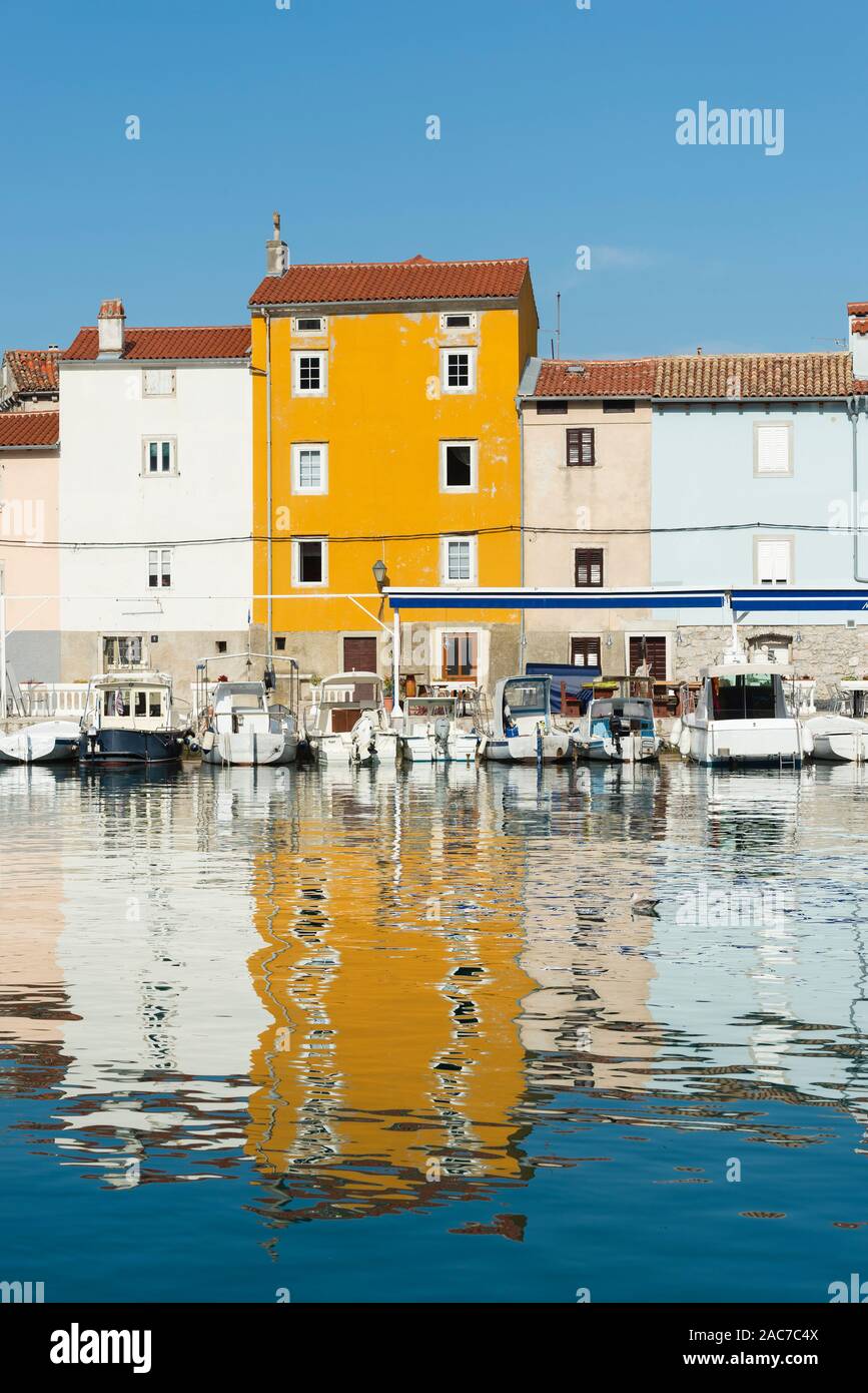 Facciate colorate nel porto della città vecchia di Cres brillano al sole di mattina e sono riflessi nell'acqua, baia di Kvarner, Croazia Foto Stock
