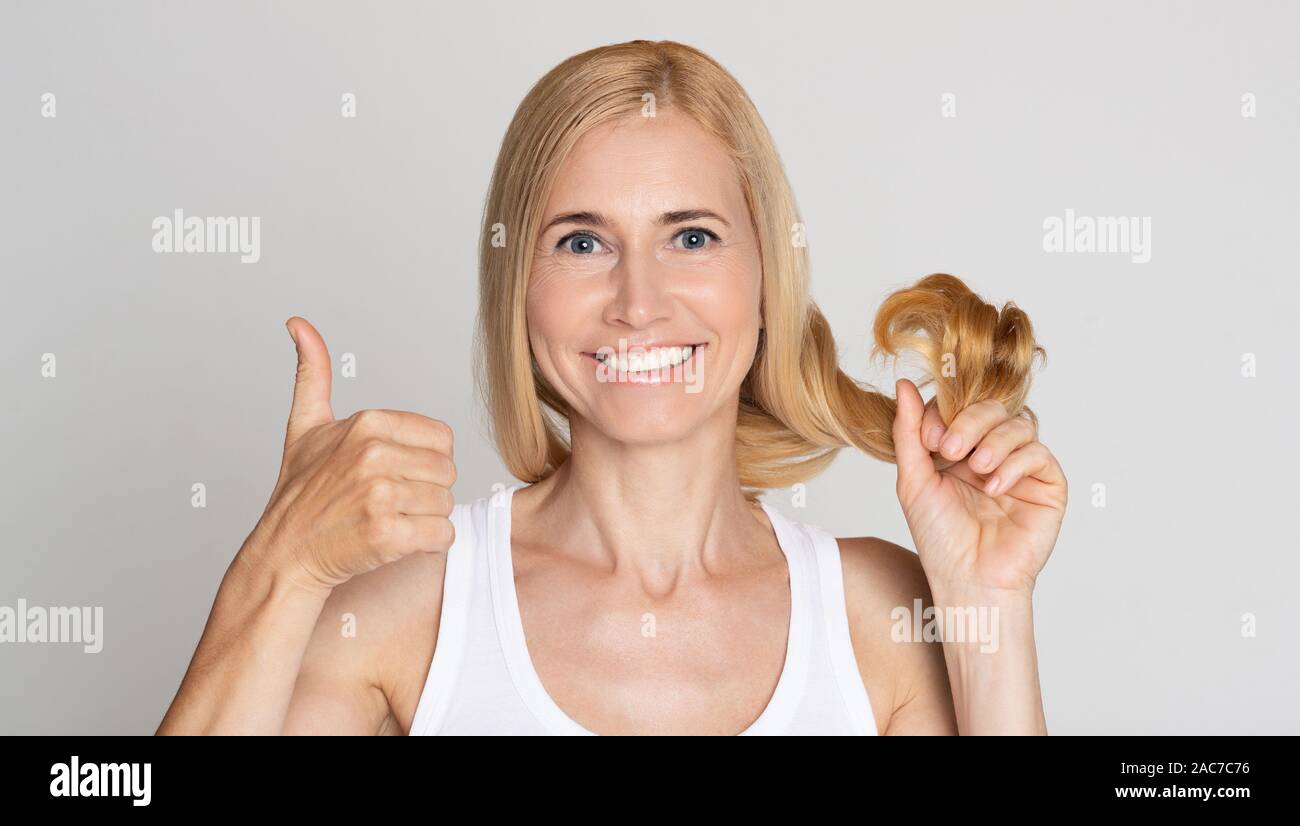 Contenti della donna che mostra i suoi capelli sani e pollice in alto Foto Stock