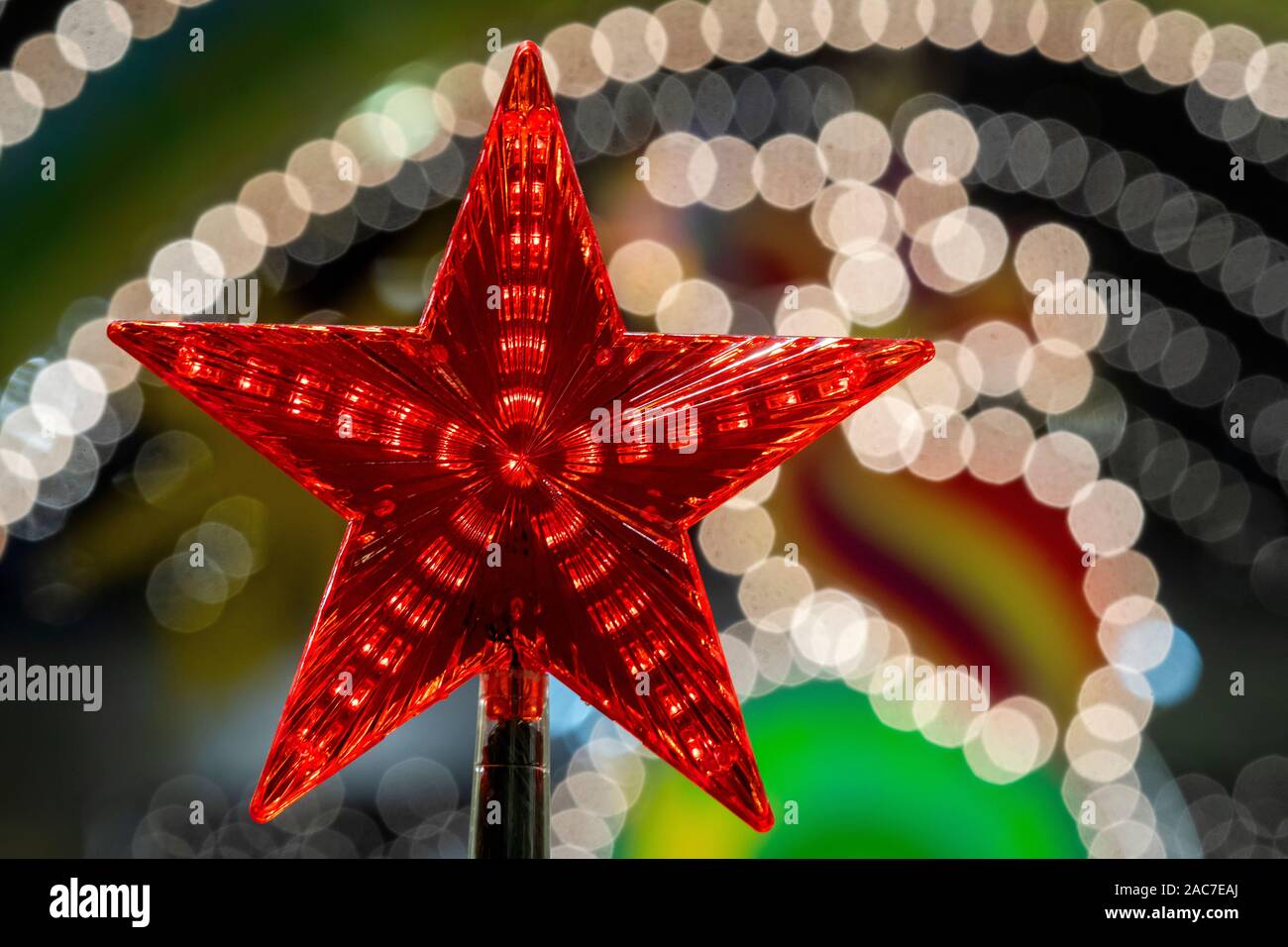 Vista ravvicinata di una stella rossa su un albero di Natale sullo sfondo di luci festive della città di notte per il nuovo anno Foto Stock