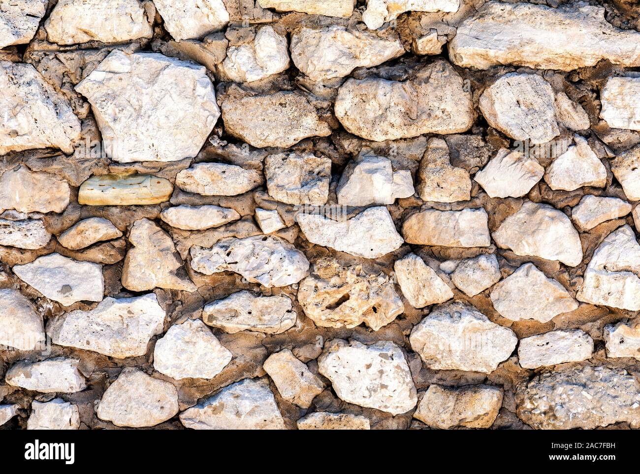 Weathered muro di pietra come creativo texture di sfondo. Le pietre naturali della muratura con cuciture irregolari. Ruvido muro di pietra texture close up Foto Stock