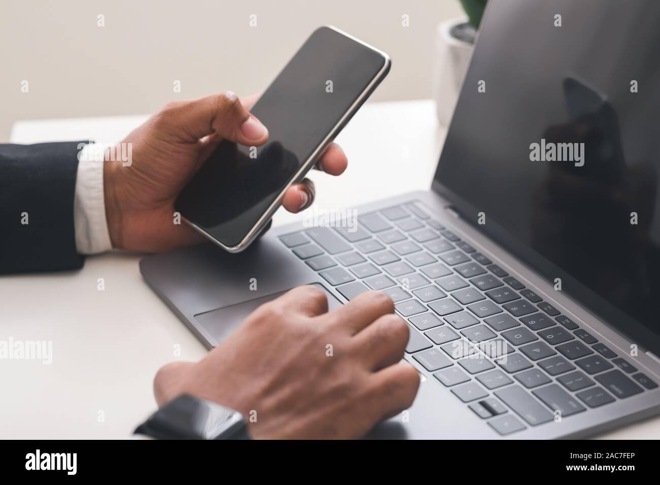 Imprenditore utilizza lo smartphone con lo schermo è vuoto e di lavoro sul computer portatile Foto Stock