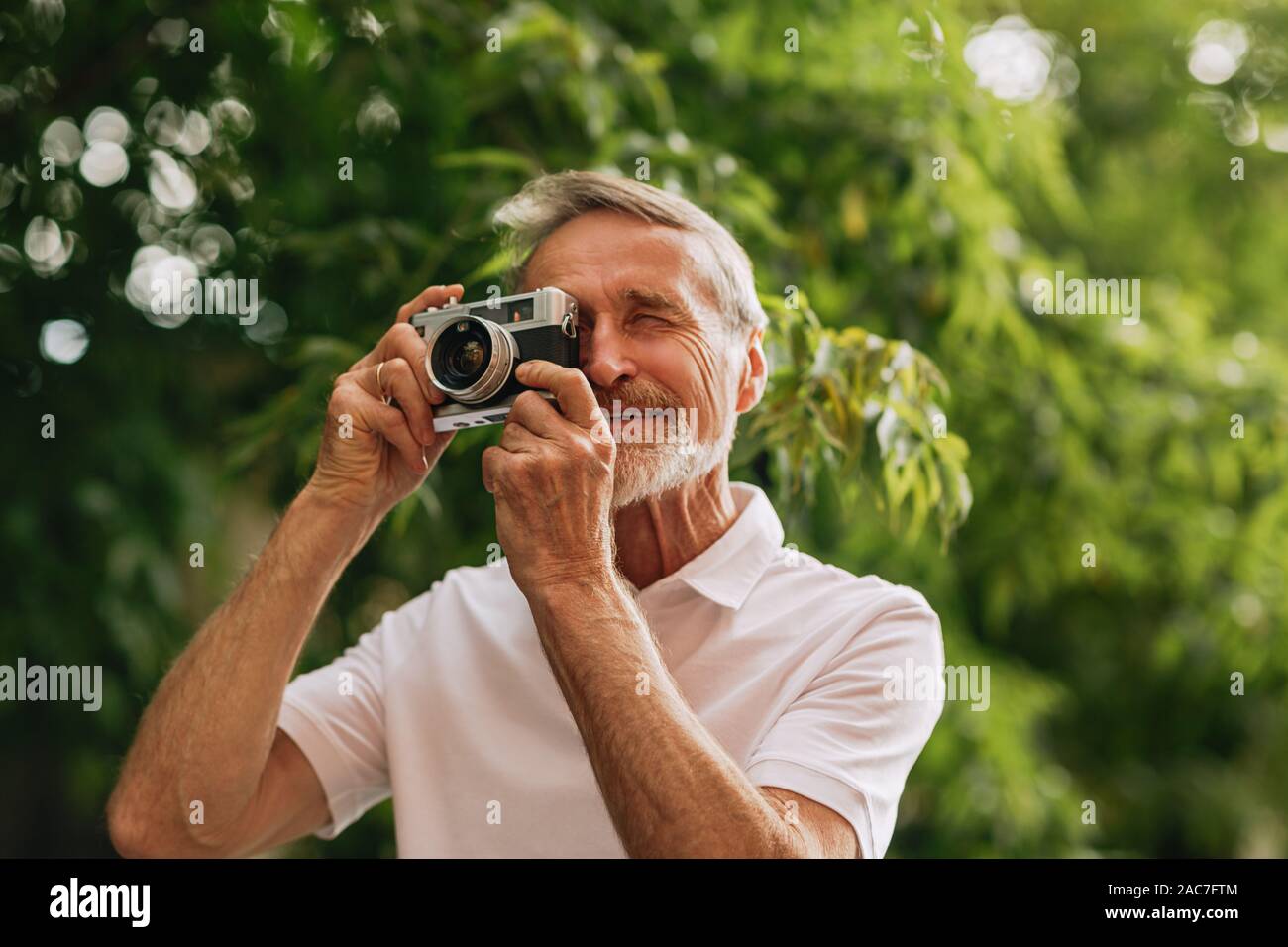 Senior uomo fare fotografie su pellicola fotocamera mentre passeggiate all'aperto Foto Stock