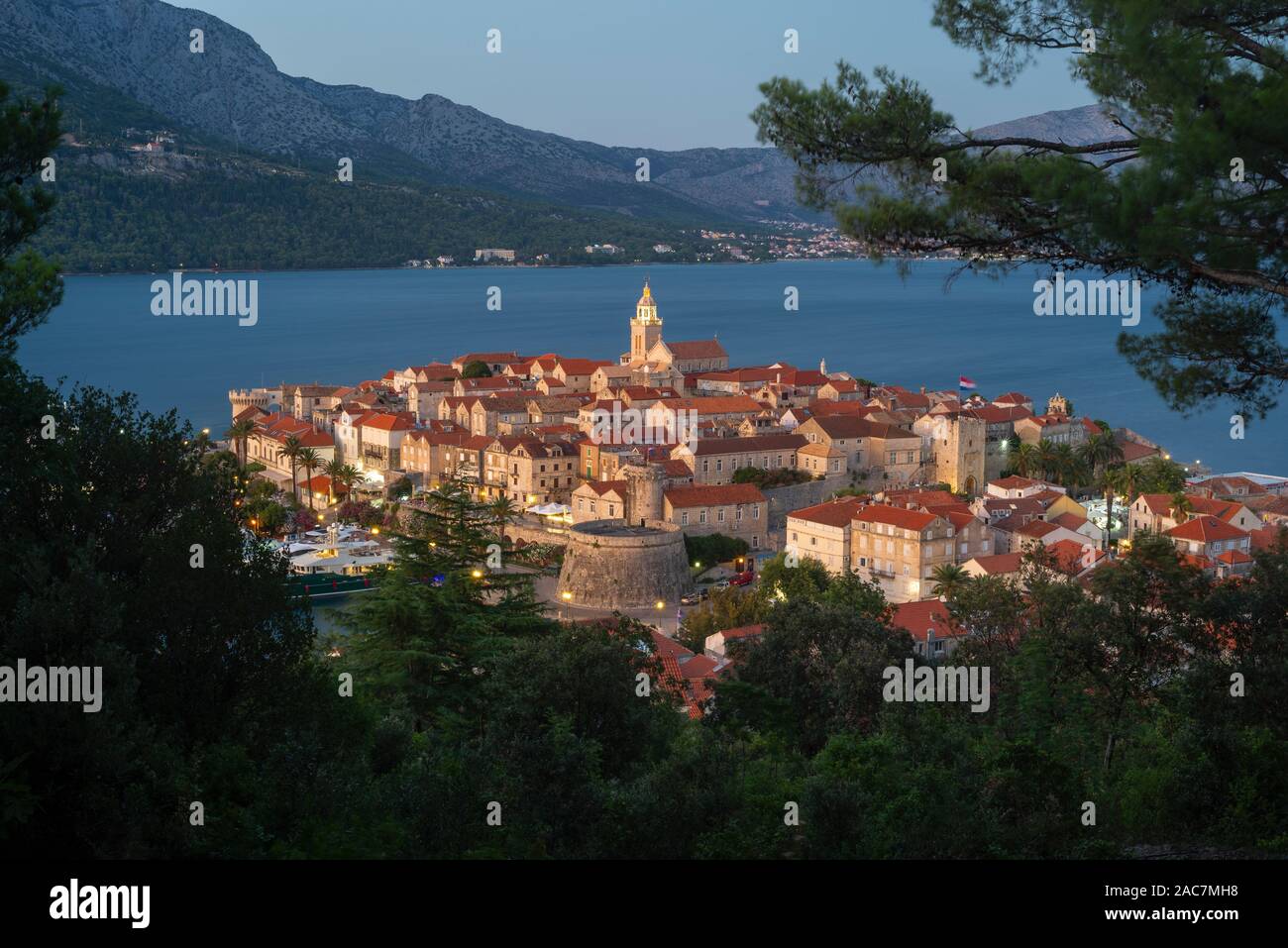 Vista di strade medievali e gli edifici del centro storico della città di Korcula di fronte all'isola di Peljesac dopo il tramonto,CROAZIA Foto Stock