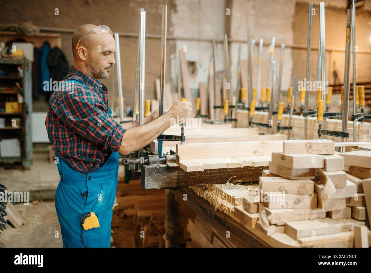 Carpenter serra il bordo in una morsa, macchine per la lavorazione del legno Foto Stock