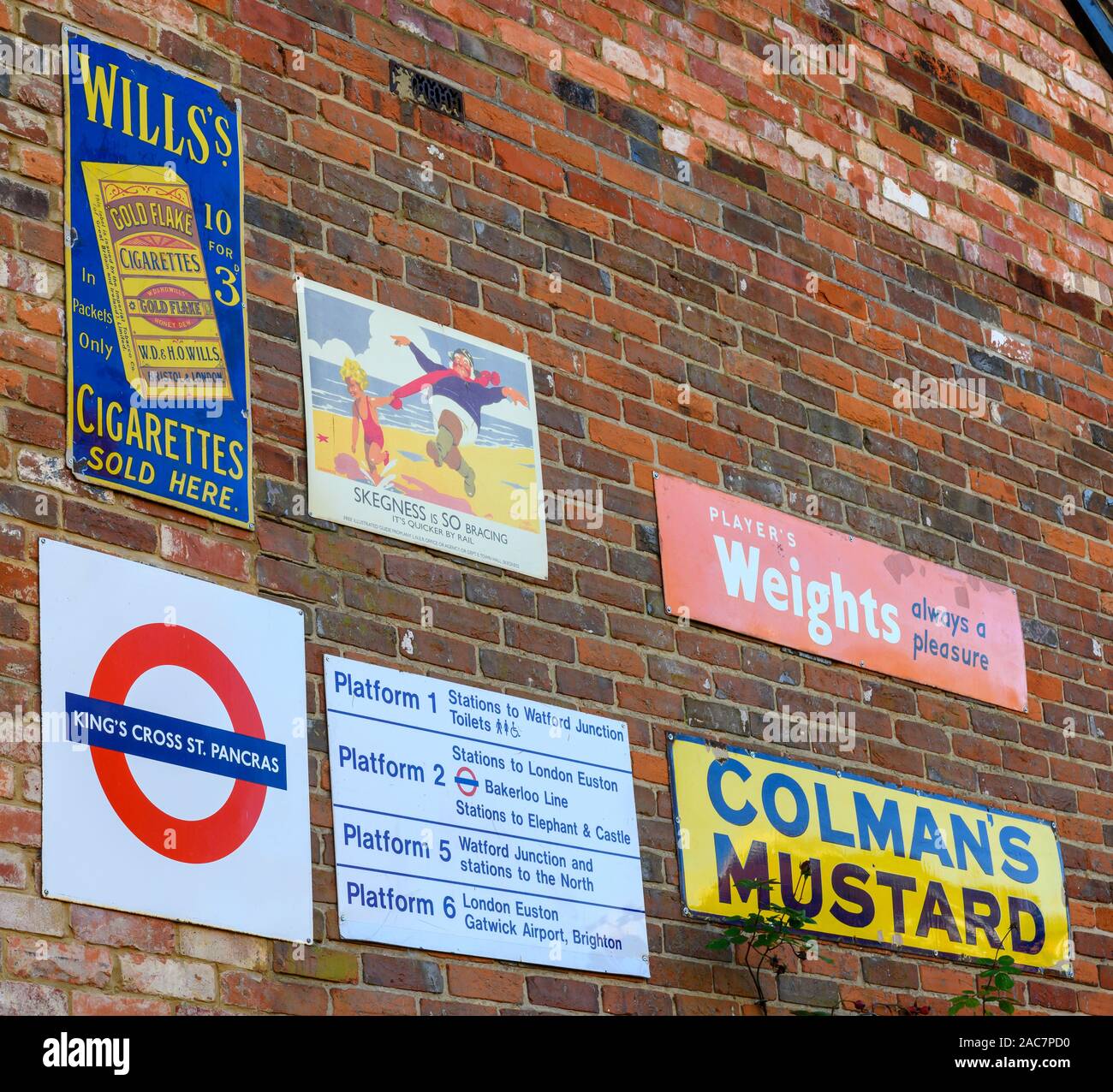 Metallo Vintage pubblicità e informazione i segni sul lato di una casa privata, Newbury Street, Whitchurch, Hampshire, Inghilterra, Regno Unito Foto Stock