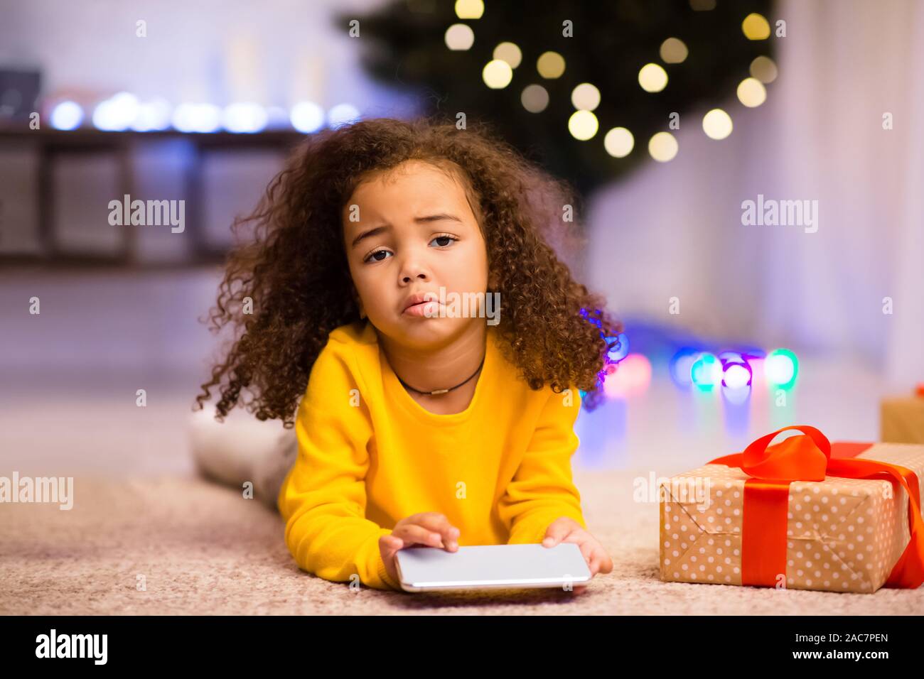 Triste african bambina con indesiderati regalo di Natale cellulare Foto Stock