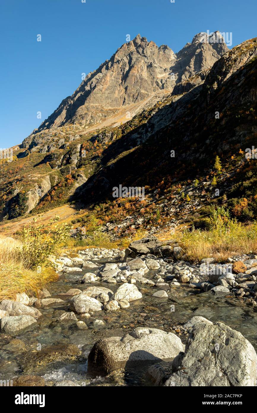 Un alto contrasto vista di un torrente che scorre verso il basso nelle Alpi con le montagne sullo sfondo Foto Stock