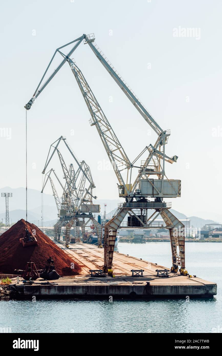 Il caricamento con gru di cucchiaia escavatore in una pila di minerale di ferro ad una banchina di carico nel porto di Ploče, Dalmazia, Croazia Foto Stock