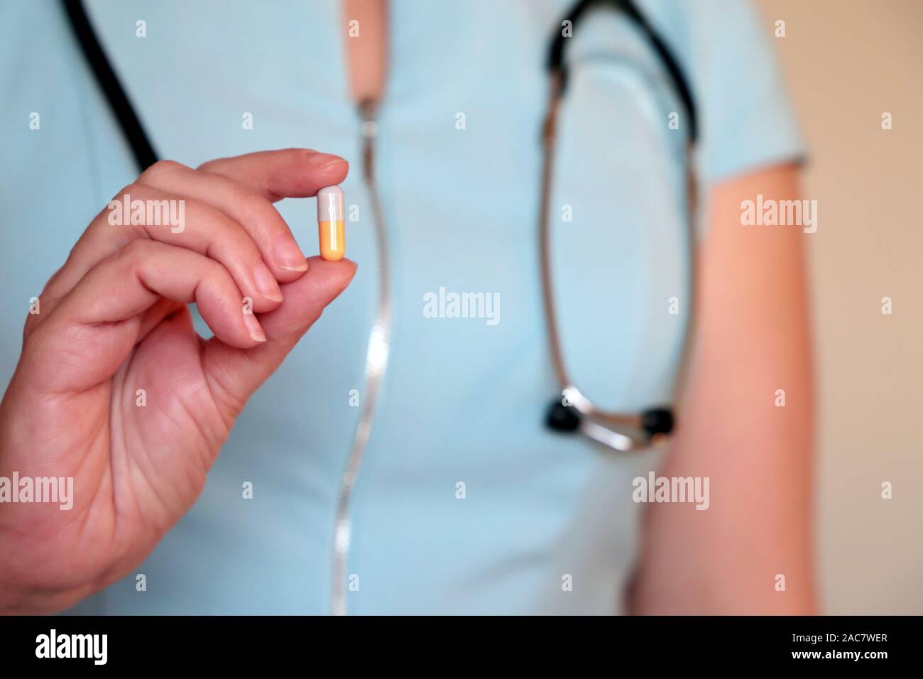 Donna medico tenendo pillola, capsula in mano femminile di close-up. Medico con farmaci, il concetto di medical exam, vitamina o di contraccettivi Foto Stock
