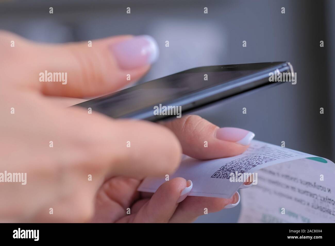Donna che utilizza smartphone e scansione del codice QR su cash shop carta ricevuta Foto Stock