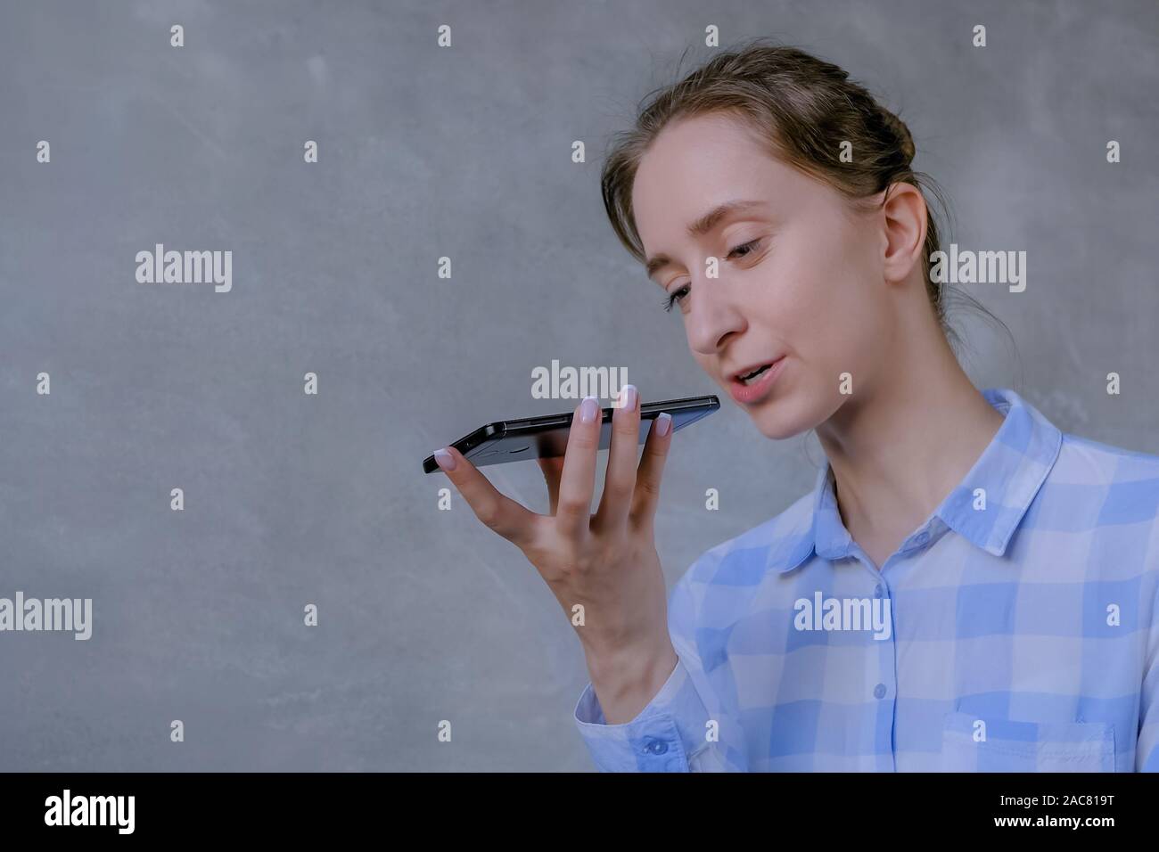 Donna che mantiene lo smartphone e con funzione di riconoscimento vocale Foto Stock