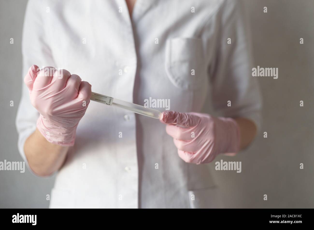 Una mano tiene un bastoncino di cotone medicale tubo Foto Stock