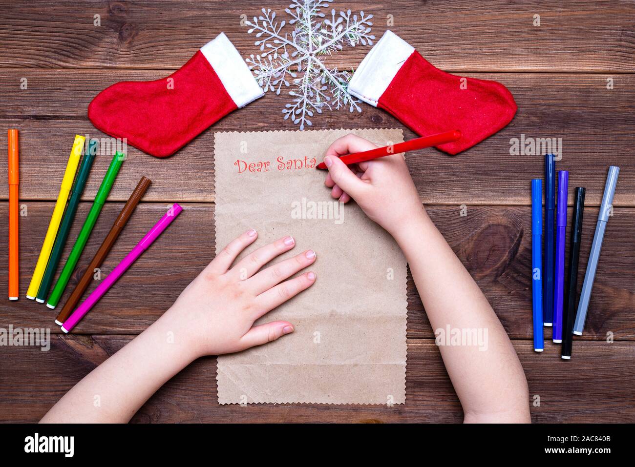 I bambini la lettera a Babbo Natale. Bambina scrive una lettera con multi-colore di pennarelli su un tavolo in legno con decorazioni di Natale sul vecchio Foto Stock