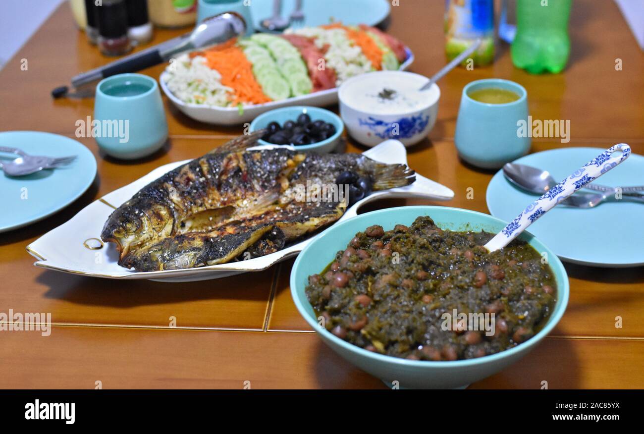 Ramadan pasto veloce con delizioso cibo iraniano che include fagioli e verdure di ghorm-e sabzi stufato, pesce alla griglia e insalata Foto Stock