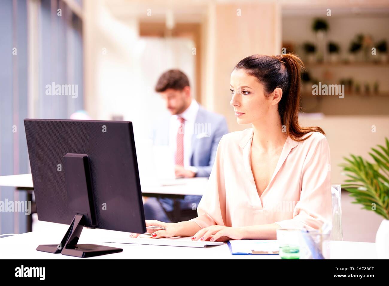 Ritratto di attraente imprenditrice lavorando sul computer in ufficio. Foto Stock