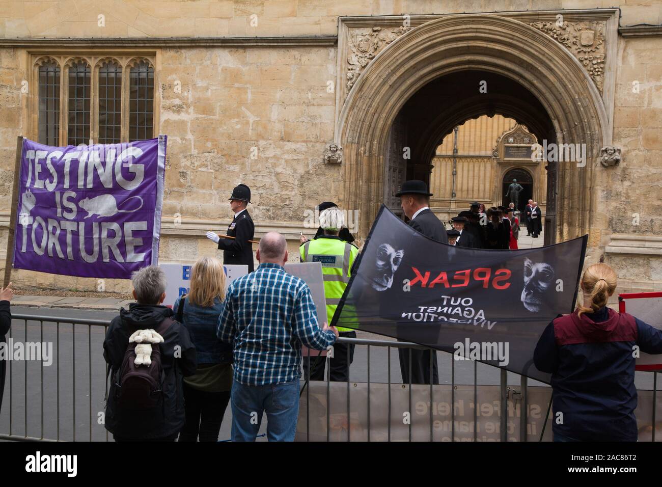 Diritti degli animali dimostranti protestano fuori la Libreria di Bodleian, Oxford come la processione Encaenium emerge dalle vecchie scuole Quad guidato da un poliziotto Foto Stock
