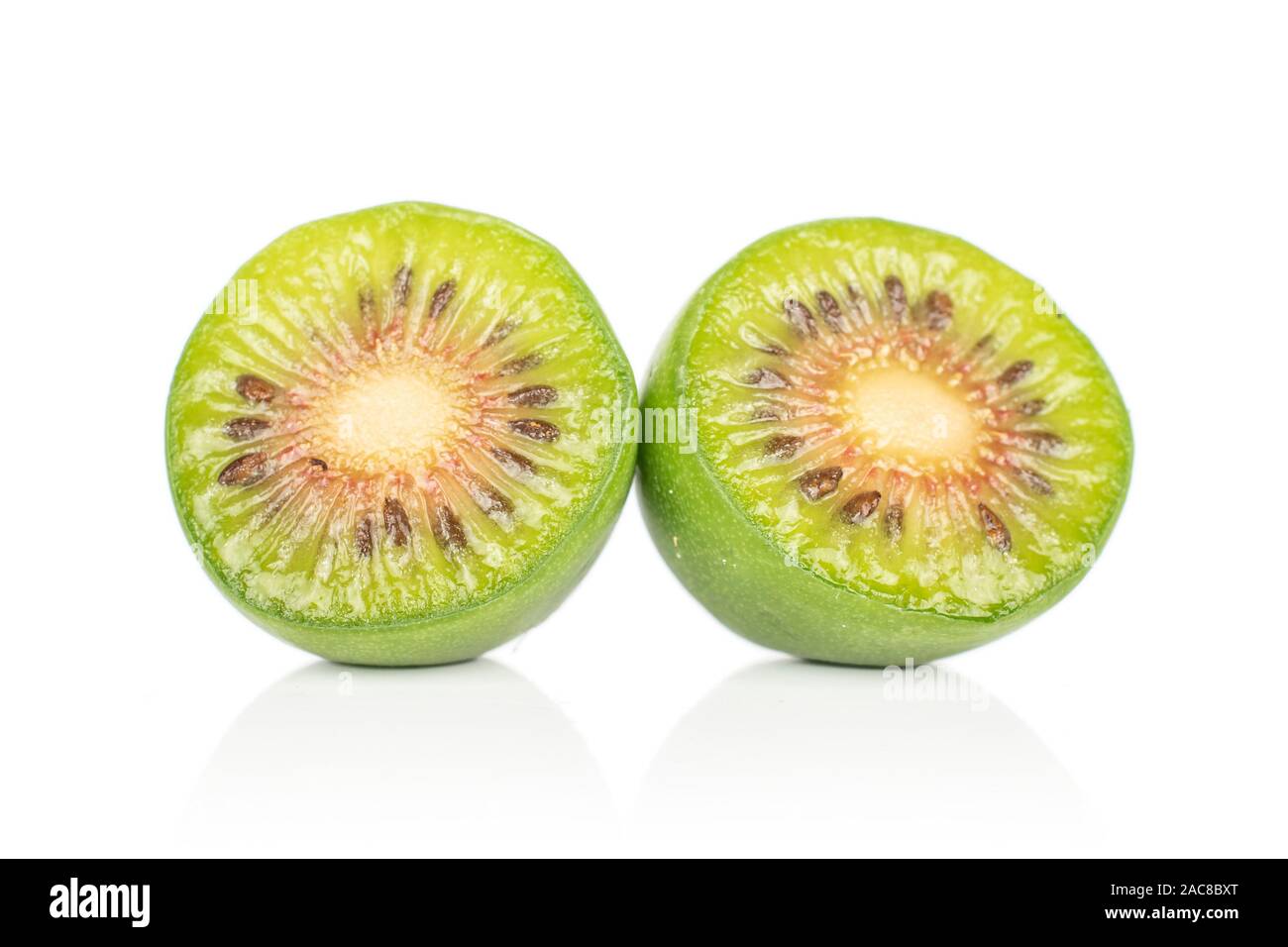 Gruppo di due metà di hardy kiwi verde uno affettato isolati su sfondo bianco Foto Stock