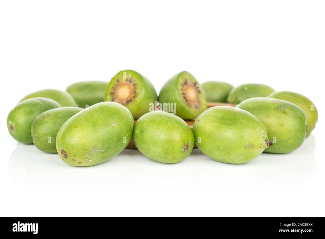 Gruppo di lotto intero di due metà di hardy kiwi verde isolato su sfondo bianco Foto Stock