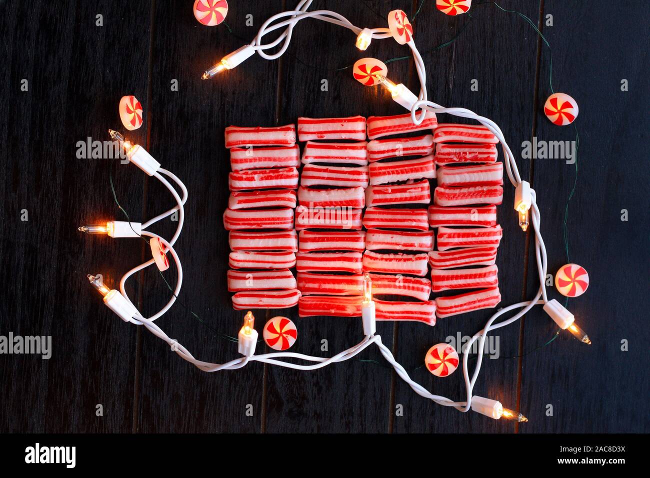 Le luci di arresto Starlight si accendono. Intorno ad alcuni mints di Natale. Su uno sfondo di legno rustico nero. Con spazio aperto sui minti per il testo per segni e cardatura Foto Stock