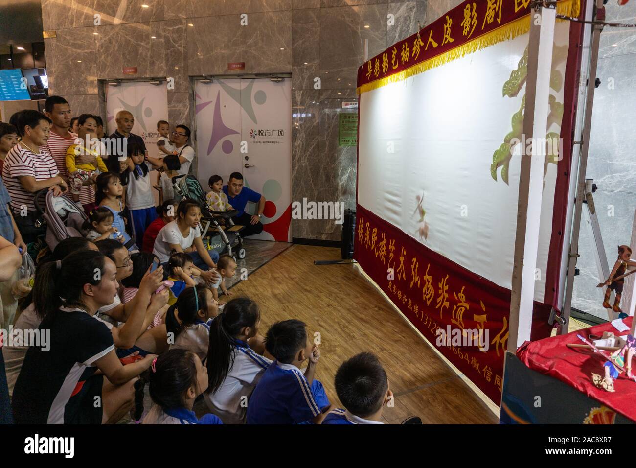 Affascinare famiglie cinesi ombra guardare uno spettacolo di burattini Foto Stock