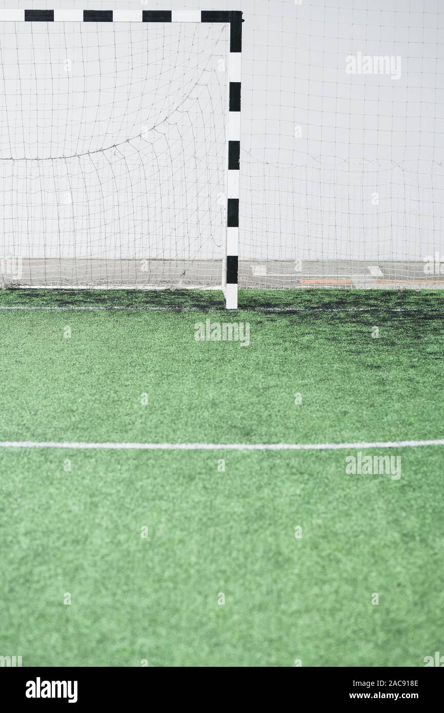Parte di verde vuoto il campo da calcio e i cancelli con net contro il muro bianco presso lo stadio contemporaneo Foto Stock