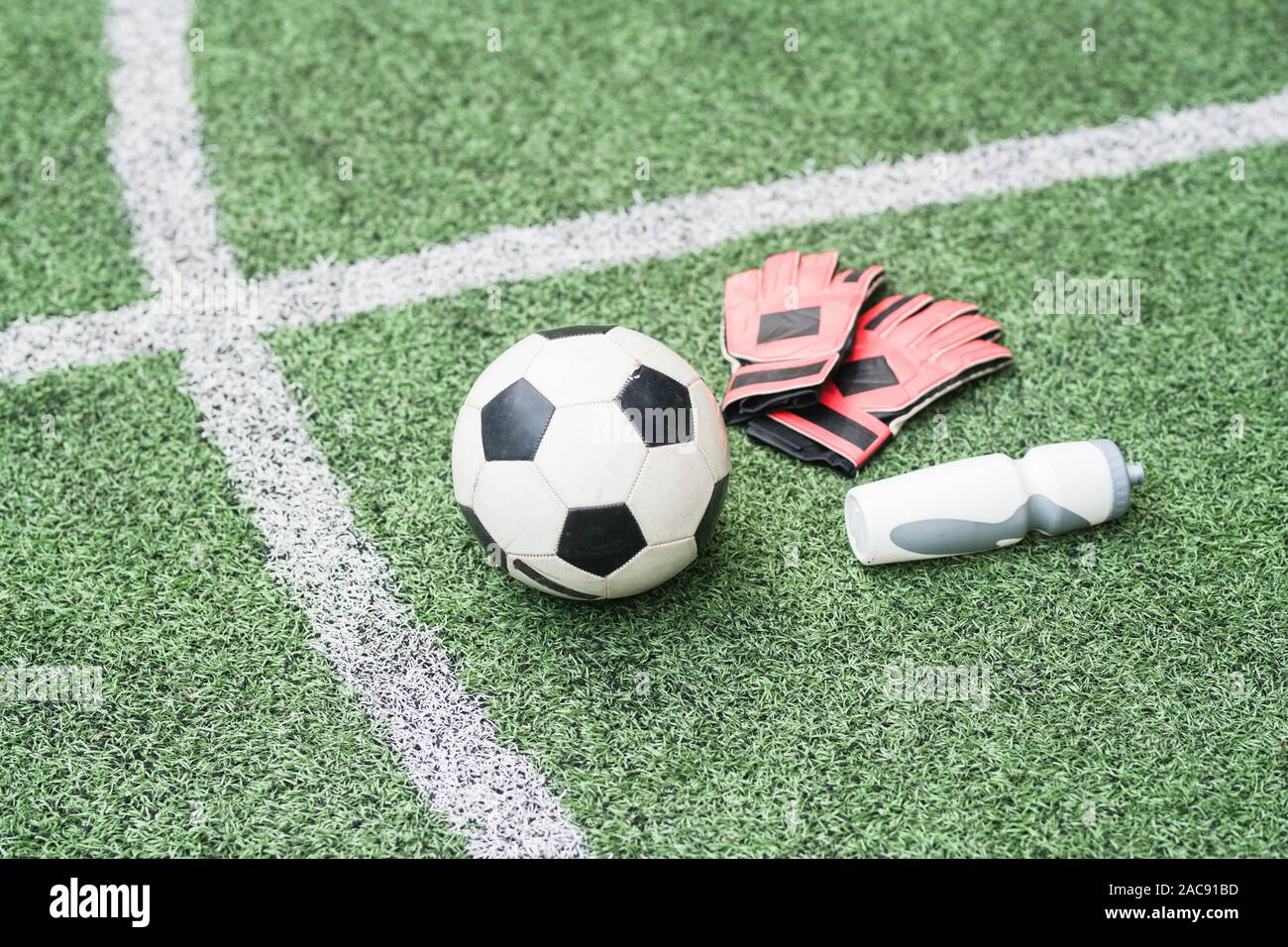 Gruppo di articoli sportivi - pallone da calcio, guanti in pelle e la bottiglia di plastica di acqua sul verde del campo di calcio Foto Stock